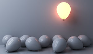 A group of balloons with one lit up and floating above the others